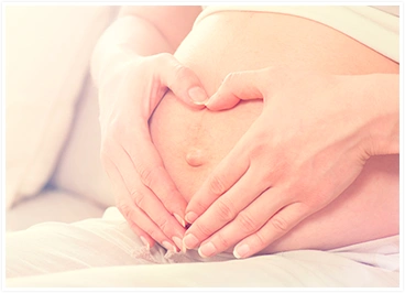 Imagem de grávida segurando a barriga formando um símbolo de coração com as mãos